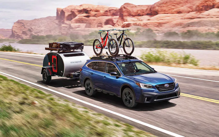 A 2022 Subaru Outback hauling a camping trailer through the desert.